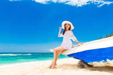 Happy young brunette in a white straw hat and white dress 