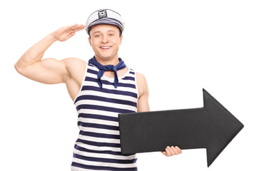 Young male sailor saluting towards the camera and holding a big