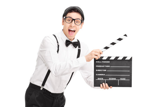 Young movie director holding a clapperboard and looking at the c