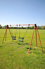 Fototapeta premium Eerie view of swings swinging on there own in a park