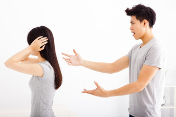 Angry young couple arguing in living room