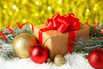 Branch of Christmas tree with balls and gift on snow