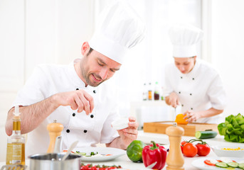 Young attractive professional chef cooking in his kitchen