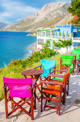 Fototapeta premium Colorful wooden chairs with view on sea, Greece