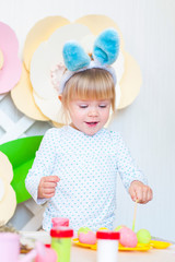 Pretty little girl painting eggs with bunny ears