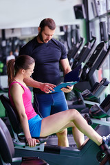 gym woman personal trainer man with weight training equipment in modern gym