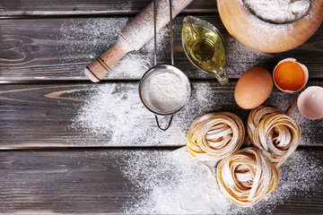 Raw homemade pasta and ingredients for pasta on wooden background