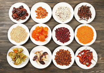 Different products on saucers on wooden background