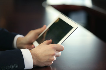 Businessman working with tablet at wooden table, closeup
