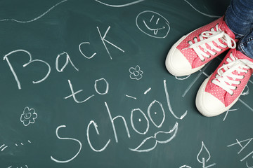 Female feet on blackboard background with inscriptions and sketches