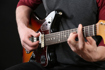 Fototapeta na wymiar Young man playing on electric guitar on dark background