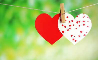 Paper hearts hanging on rope on bright background