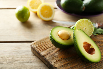 Sliced avocado and lemon lime on cutting board, on wooden background