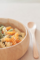 Raw fusilli pasta on wooden bowl