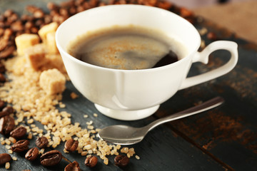 Cup of coffee with beans on table, closeup