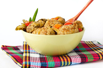 Тефтели с овощами на клетчатой салфетке. Белый фон