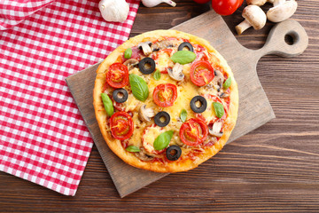 Tasty pizza with vegetables and basil on table close up