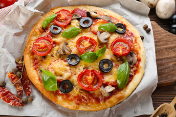 Tasty pizza with vegetables and basil on table close up