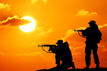 Fototapeta na wymiar Silhouette shot of soldier holding gun with colorful sky and mou