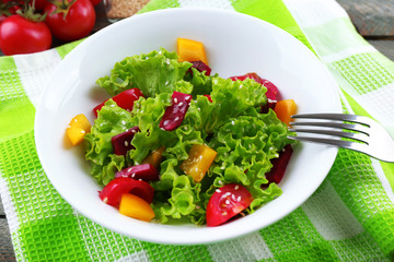Bowl of fresh green salad on table with napkin, closeup