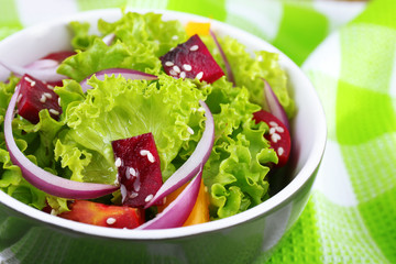 Bowl of fresh green salad on table with napkin, closeup