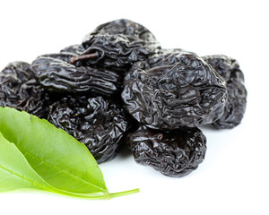 Pile of prunes with green leaves isolated on white