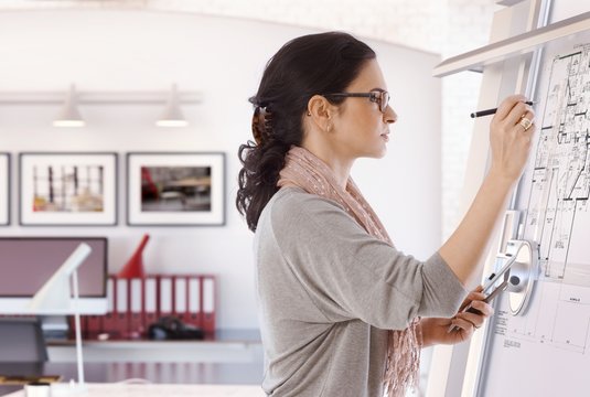 Focused female architect working on drawing board