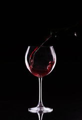 bottle and glass with red wine on a black background