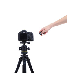 Camera with the lens on tripod. Hand presses the shutter or remo