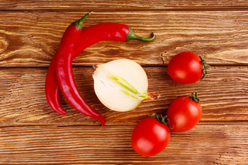 Red hot cherry and chili peppers over white wooden background onion