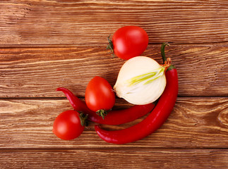 Red hot cherry and chili peppers over white wooden background onion