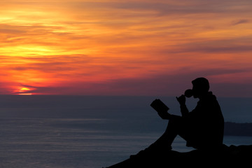 Fototapeta na wymiar Silhouette of a man sitting on breakwater in evening near sea, r