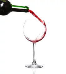 Fotobehang Red wine pouring from bottle into big glass on white background © YURII Seleznov