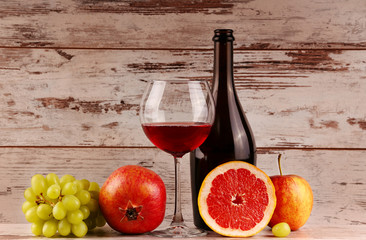 Red wine bottle on a wooden background, apple and pomegranate