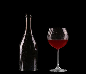 Elegant red wine glass and a wine bottle in black background