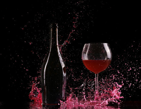 Glass And Bottle Of Red Wine Splash On Black