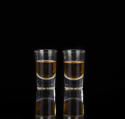 Two glasses of whiskey on black table