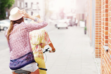 Two girl friends riding tandem bicycle