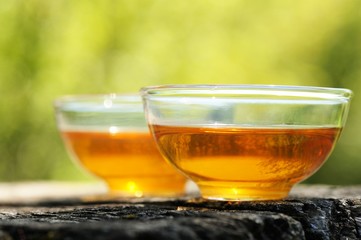 Two glass cups of black tea  on old wooden board in bright sunli
