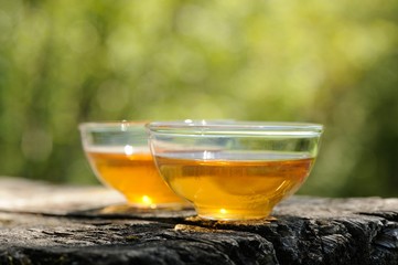 Two glass cups of black tea  on old wooden board in bright sunli