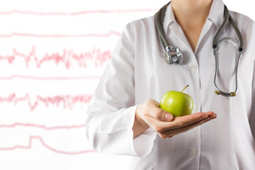 Doctor's hand holding green apple on blurred medical background