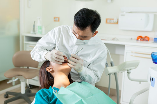 Asian Dentist Is Doing A Dental Checkup To A Young Asian Woman