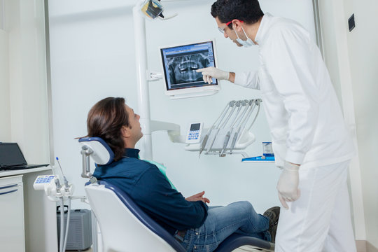 Dentist is showing his patient on the monitor what he is going t