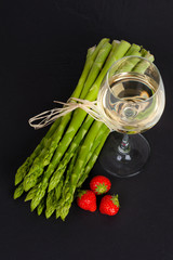Grüner Spargel mit Weißwein und Erdbeeren auf Schiefer