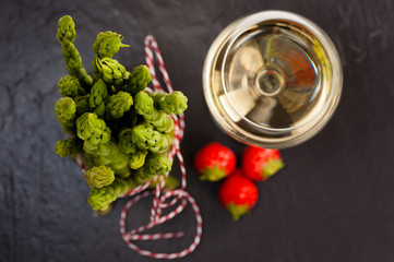 Grüner Spargel mit Weißwein und Erdbeeren auf Schiefer, Topshot