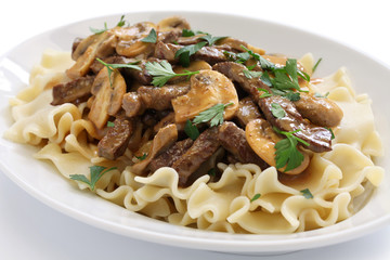 beef stroganoff with pasta, russian cuisine on white background