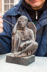 Hands of sculptor clean bronze sculpture with brush