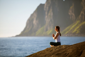 Naklejka na ściany i meble Young woman is practicing yoga between mountains in Norway