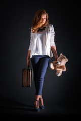 Pretty woman with suitcase and bear toy isolated, studio shot