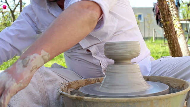 hands of a potter, creating a clay jar